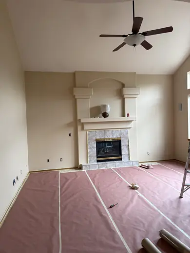 Living room with fireplace and floors covered in protective paper, Elements Painting project on the Colorado Front Range