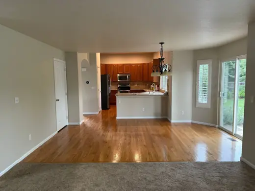 Living room with hardwood floors opening to kitchen, neutral walls, Elements Painting project on the Colorado Front Range