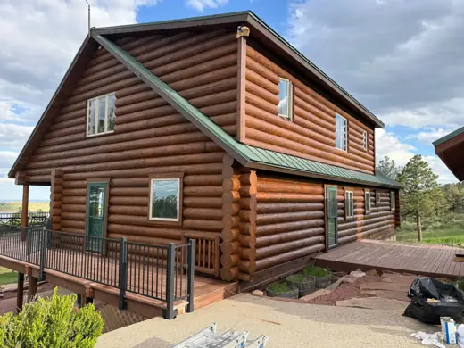 Log cabin exterior with green metal roof and fresh stain, Elements Painting project on the Colorado Front Range