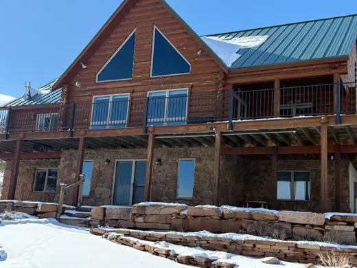 Log home rear with tall windows, green roof and deck, Elements Painting project on the Colorado Front Range