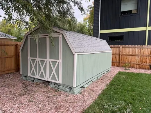 Sage green shed with white trim by wood fence, Elements Painting project on the Colorado Front Range