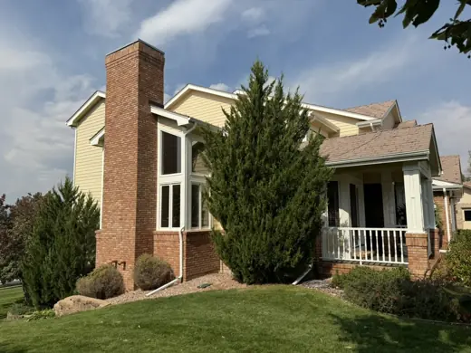 Tan two-story home with brick chimney and shrubs, Elements Painting project on the Colorado Front Range