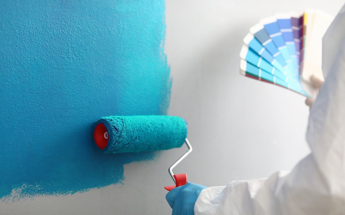 Master painter holds in his hands color palette with shades of blue