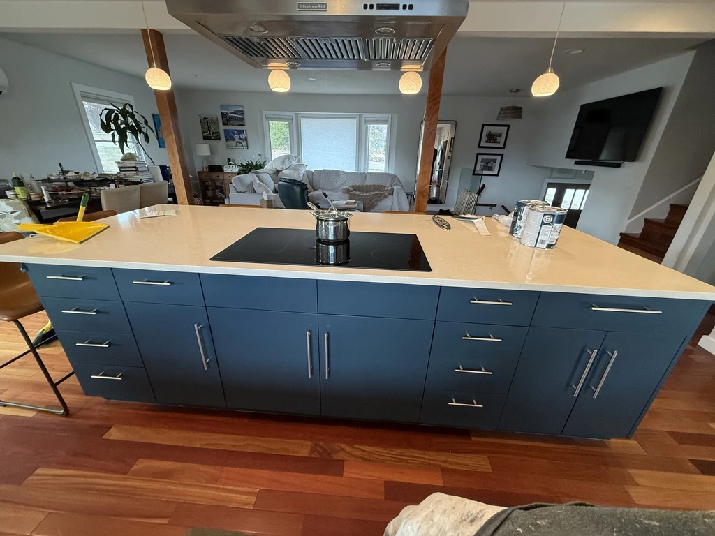 Expert Kitchen Island Cabinet Painting for a Modern Look Close up of a freshly painted dark blue kitchen island with light countertops and hardwood flooring.