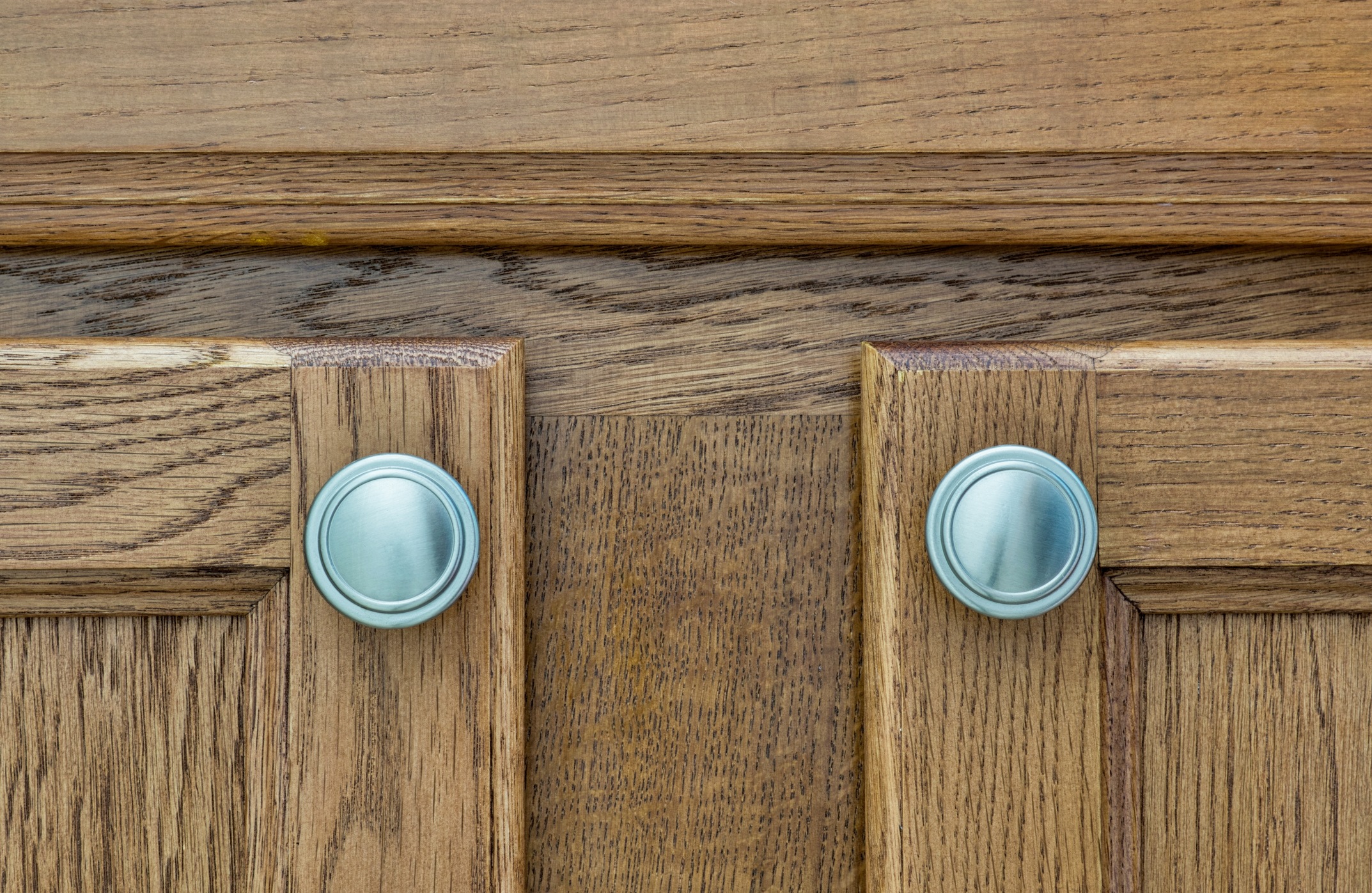 Closeup of brown wooden cupboard doors and handles.